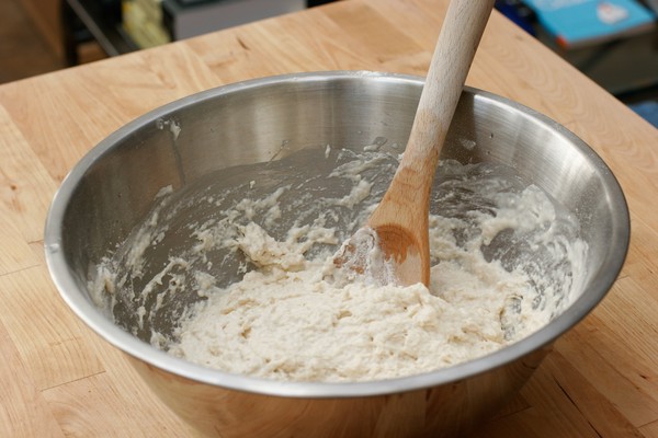 Cookie dough A metal mixing bowl with dough and a wooden spoon in it