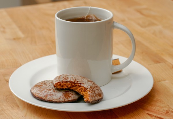Holiday spice cookies with tea A cup of tea with two holiday spice cookies on the saucer; one cookie has a bite taken out of it