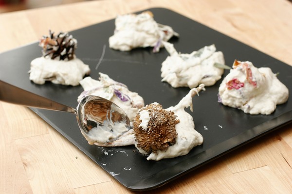 Spooning cookies Six mounds of dough with large pieces of potpourri sticking out of them on a cookie sheet; a metal spoon is depositing the last mound
