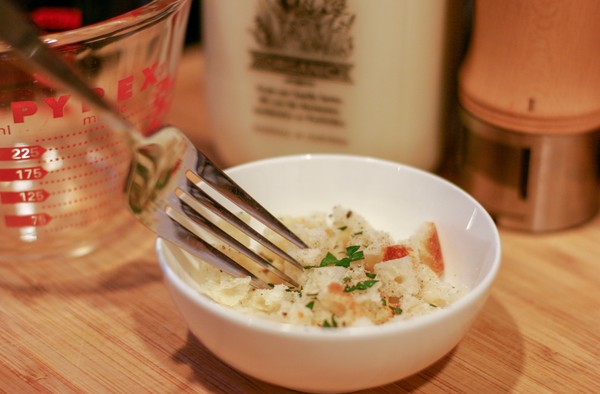Stuffing for personal turkey A tiny white bowl filled with some bread crumbs and parsley, being mixed with a fork; a measuring cup, a bottle of milk, and a pepper grinder are in the background