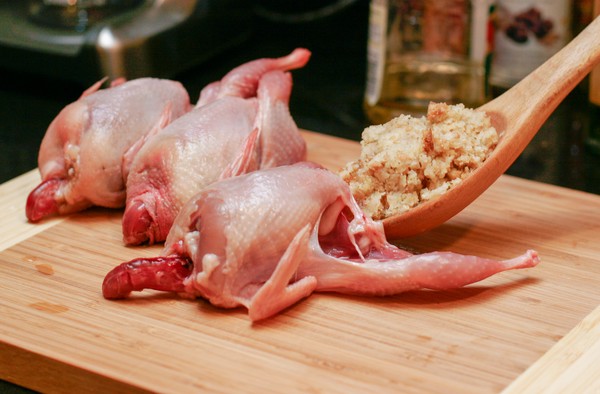 Stuffing the personal turkey Three small headless, plucked birds on a cutting board; a wooden spoon is being used to shove a mound of stuffing into one of the birds