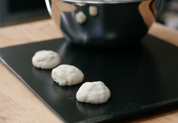 Formed Swedish Lemon Tea Biscuits Three mounds of light-colored cookie dough on a cookie sheet with a metal bowl in the background