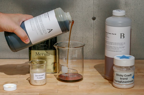 Bottle of unknown substance labeled, 'A' being poured into large beaker with other bottles/beakers nearby