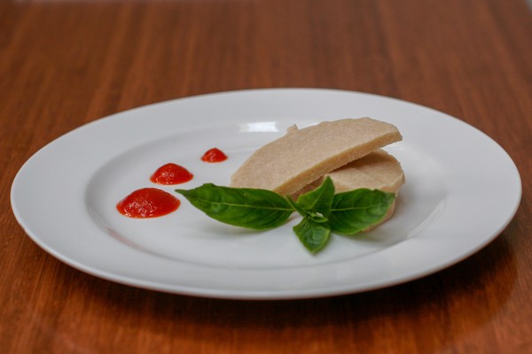 Sliced and plated expanding meat Two slices of vegetarian ham on a plate with basil and artsy hot sauce dollops