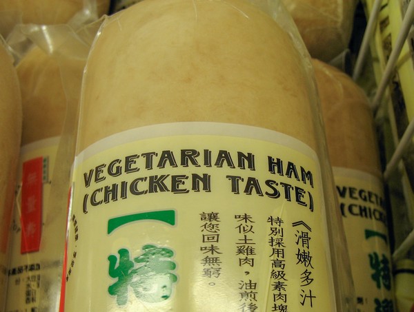 A loaf of vegetarian ham (chicken taste) in a supermarket freezer on top of other loaves in the background